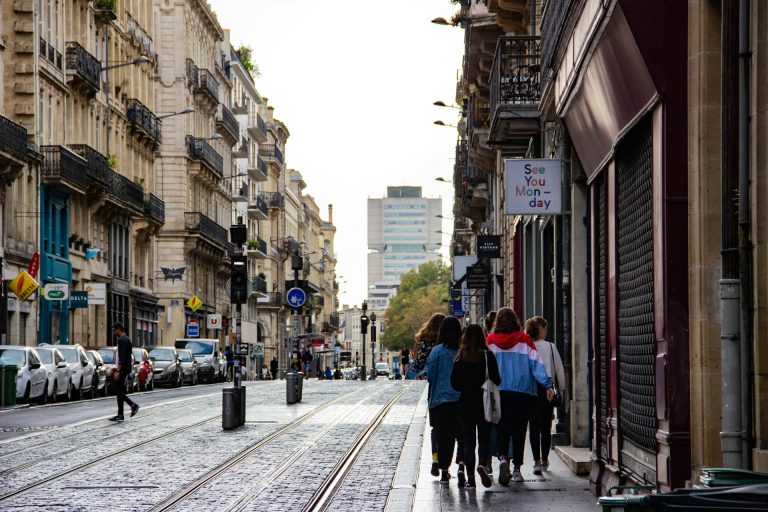Photo d'une rue typique de Bordeaux avec ses piétons et voitures garées