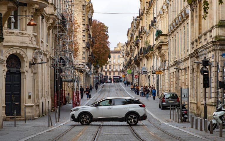 Une voiture traverse une rue typique du centre-ville de Bordeaux